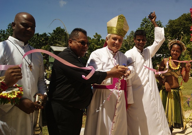 Bishop Cappelli cuts the ribbon assist by some of the parish priest from oversea 